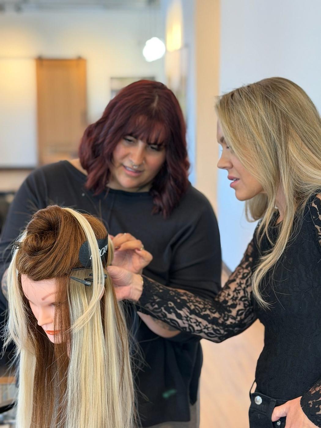 An educator guiding a stylist through a no-sew butterfly weft install at a hands-on class