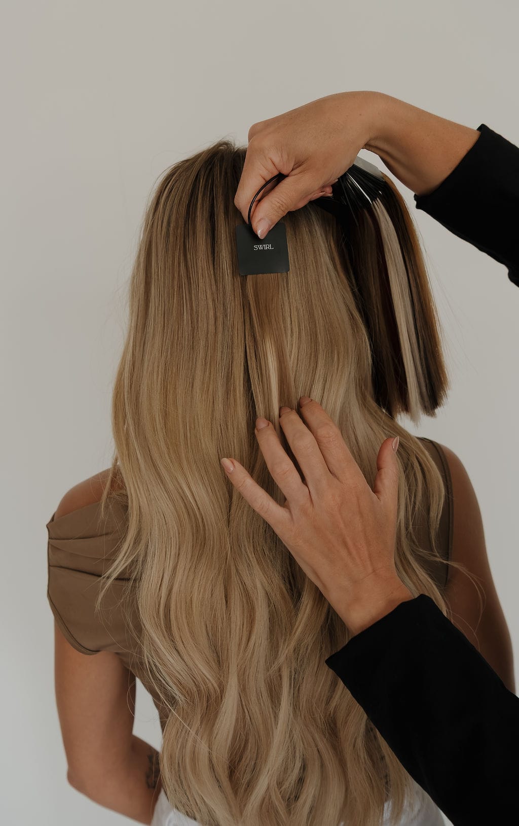 Two stylists placing an Adorn weft in long blonde hair