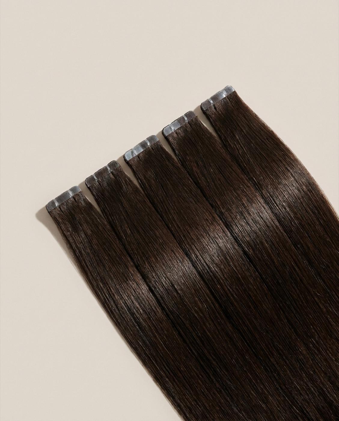 Dark brunette tape-in wefts fanned, tabs showing